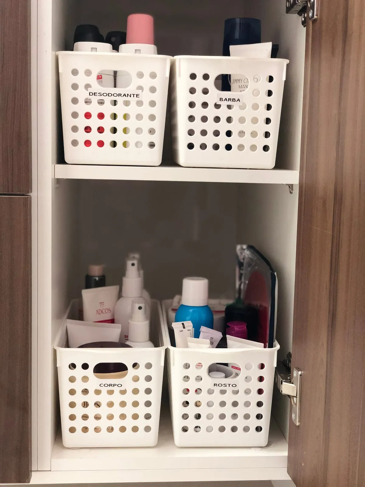 Armario de baño con cestas blancas etiquetadas en dos baldas, cada una con un tipo de producto.